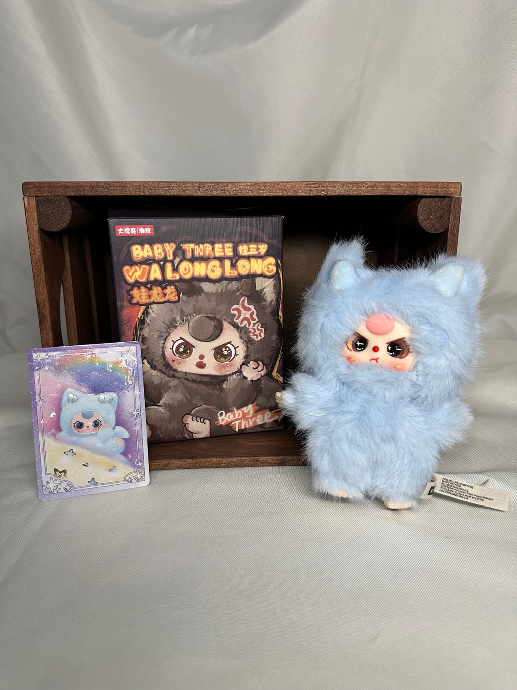Baby Three Splashy blue dragon plush displayed beside its open box and character card