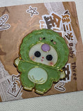 Baby Three Dino enamel pin in green with a pale belly and purple forehead accent on backing card