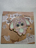 Baby Three Pink Bunny enamel pin with floppy ears, pale belly, and purple forehead accent on backing card