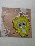 Baby Three Lion enamel pin in yellow with a pale belly and gold-colored outlines on backing card